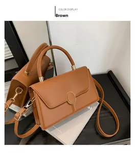 Dettaglio della pelle marrone opaca e della chiusura circolare dorata della borsa a mano