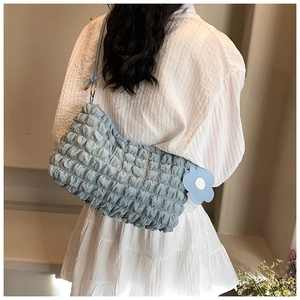 Close-up of light blue bubble textured shoulder bag with floral charm and metal rings