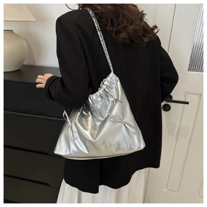 Detail of silver metallic drawstring bag with bow accents and elegant chain strap