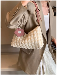 Detail of white bubble texture bag with pink handle and floral charm on a model