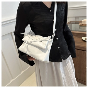 Détail d'un sac à bandoulière blanc avec un nœud élégant et une texture en cuir souple