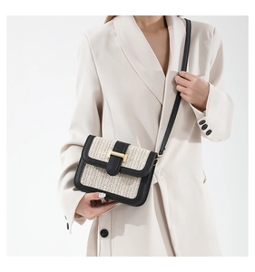 Detail of minimalist straw woven crossbody bag with black leather trim and golden metal clasp