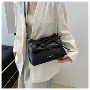 Détail du sac bandoulière en cuir noir avec nœud décoratif et lettrage blanc élégant