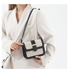 Détail du tissage en paille contrasté et boucle en H dorée sur un sac bandoulière