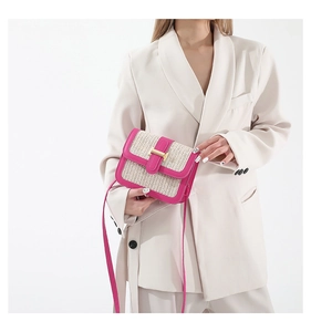 Detail of hand-woven beige straw crossbody bag with pink leather trim and gold buckle
