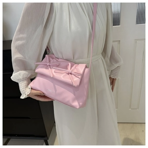 Détail d'un sac bandoulière en cuir PU rose tendre orné de deux nœuds décoratifs