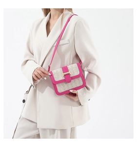 Détail du sac bandoulière en paille tressée avec bordure en cuir rose et boucle H dorée