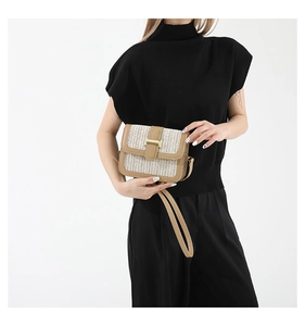Detail of woven straw handbag featuring tan leather trim and golden metal clasp