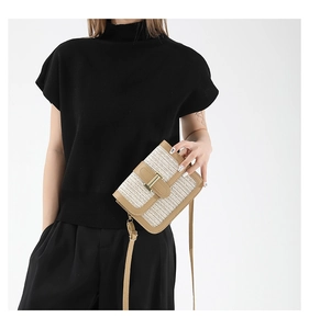 Detail of hand-woven crossbody bag featuring contrast leather trim and golden metal clasp