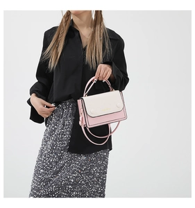Détail du sac bandoulière rose et beige avec boucle dorée porté sur une jupe à paillettes