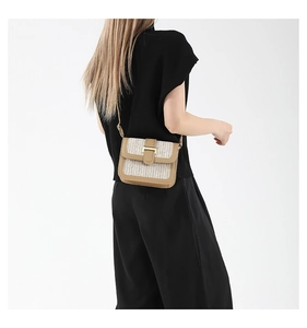 Détail du sac bandoulière en paille tressée avec bordure en cuir brun et boucle dorée