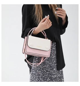 Détail du sac bandoulière rose et blanc avec logo doré et boucles rondes