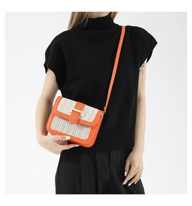 Détail du petit sac bandoulière en paille tissée avec garniture en cuir orange vif