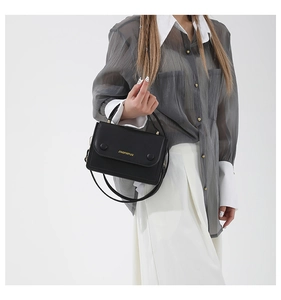 Détail d'un sac bandoulière noir chic avec texte doré et bandoulière réglable