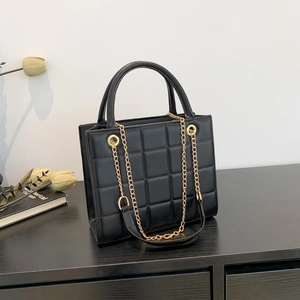 Classic black quilted crossbody bag with gold chain strap and rigid top handle