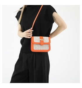 Détail d'un sac bandoulière orange et beige avec boucle métallique dorée et texture tissée