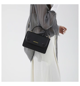 Vue latérale du sac bandoulière en cuir noir avec détails dorés et poignée haute
