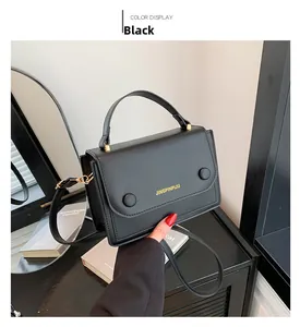 Détail d'un sac bandoulière noir avec lettrage doré et deux boutons décoratifs