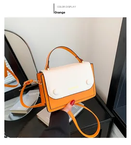 Détail du sac à main montrant le corps orange et le rabat blanc avec fermoir en métal
