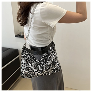 Detail einer schwarz-silbernen Pailletten-Handtasche mit Kette am Modell getragen