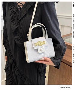 Gros plan du sac blanc motif crocodile avec boucle dorée ondulée élégante