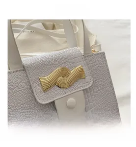 Détail du sac blanc en cuir crocodile avec fermoir métallique doré ondulé élégant