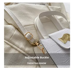 Détail du sac blanc à motif crocodile avec boucle dorée ondulée et bandoulière réglable