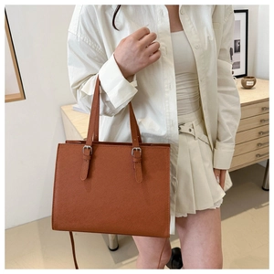 Detail of tan tote bag with cross-grain texture and adjustable silver buckle straps