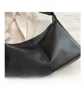 Dettaglio della borsa sottobraccio in pelle nera opaca con cuciture verticali e stile retro
