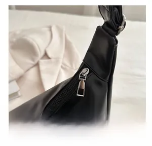 Dettaglio della zip argentata e della larga tracolla in pelle della borsa nera tote