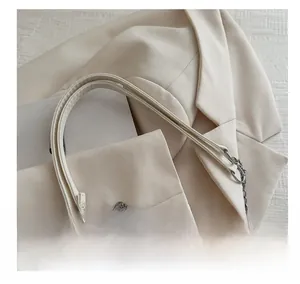 Détail de la poignée confortable et de la chaîne argentée sur le sac en cuir blanc