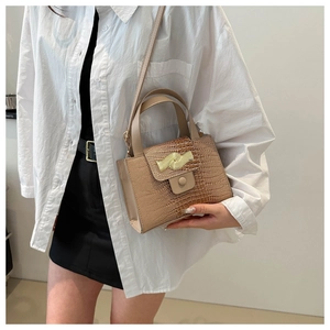 Détail du sac bandoulière gaufré croco avec boucle dorée ondulée et poignée ronde