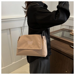 Vue détaillée de la broderie papillon rose et de la chaîne en métal du sac beige