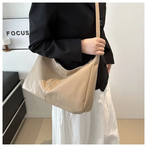 Dettaglio della borsa hobo beige in ecopelle indossata dalla modella in abito