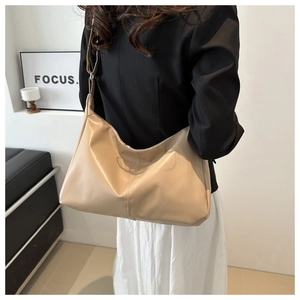 Dettaglio della borsa a secchiello beige caldo con cuciture verticali e tracolla regolabile