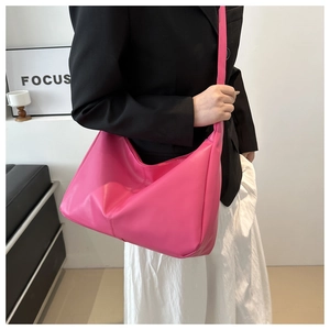 Vista laterale della grande borsa tote rosa in morbida ecopelle indossata dal modello