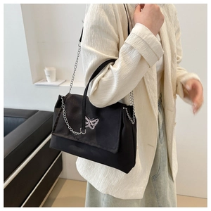 Detail view of black PU shoulder bag with butterfly embroidery and silver chain on model