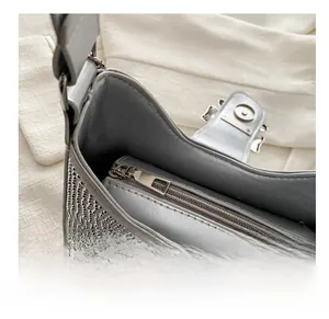 Gros plan sur la fermeture éclair lisse et la doublure soyeuse du sac en strass argentés
