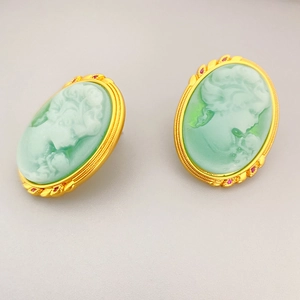 Vintage style cameo earrings with green relief and red gemstone accents in gold frame