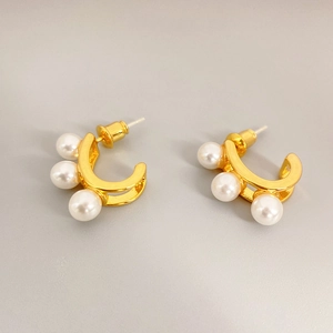 Polished C-shaped gold-plated stud earrings with three white pearls on a grey background