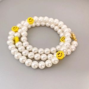 Elegant pearl choker necklace featuring yellow smiley face charms and gold lobster clasp