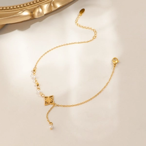 Titanium steel anklet with gold flower charm, pearls and tassels on a luxury background