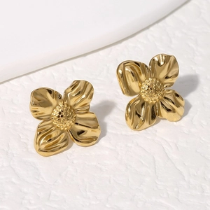 Elegant gold flower stud earrings with textured petals and vintage relief on stone surface
