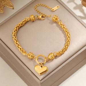 Golden titanium steel woven chain bracelet with heart pendant on a jewelry box