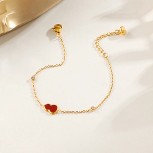 Gold chain bracelet with red gourd pendant and crystals against an elegant shadow backdrop