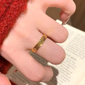 Polished gold plated titanium steel ring with cat-eye wave texture on a female finger