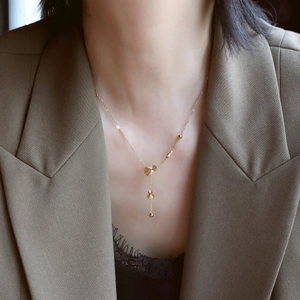 Close-up of golden heart-shaped pleated fan pendant necklace on a model wearing a suit