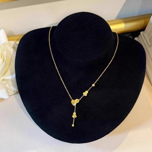 Elegant gold Y-shaped necklace with heart pendants and beads on a black display stand