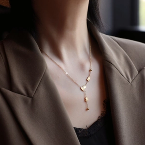 Elegant gold Y-shaped necklace featuring ginkgo leaf pendants and delicate beads style