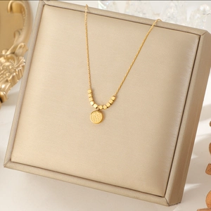 Golden titanium steel necklace with a round Fu character pendant on jewelry box